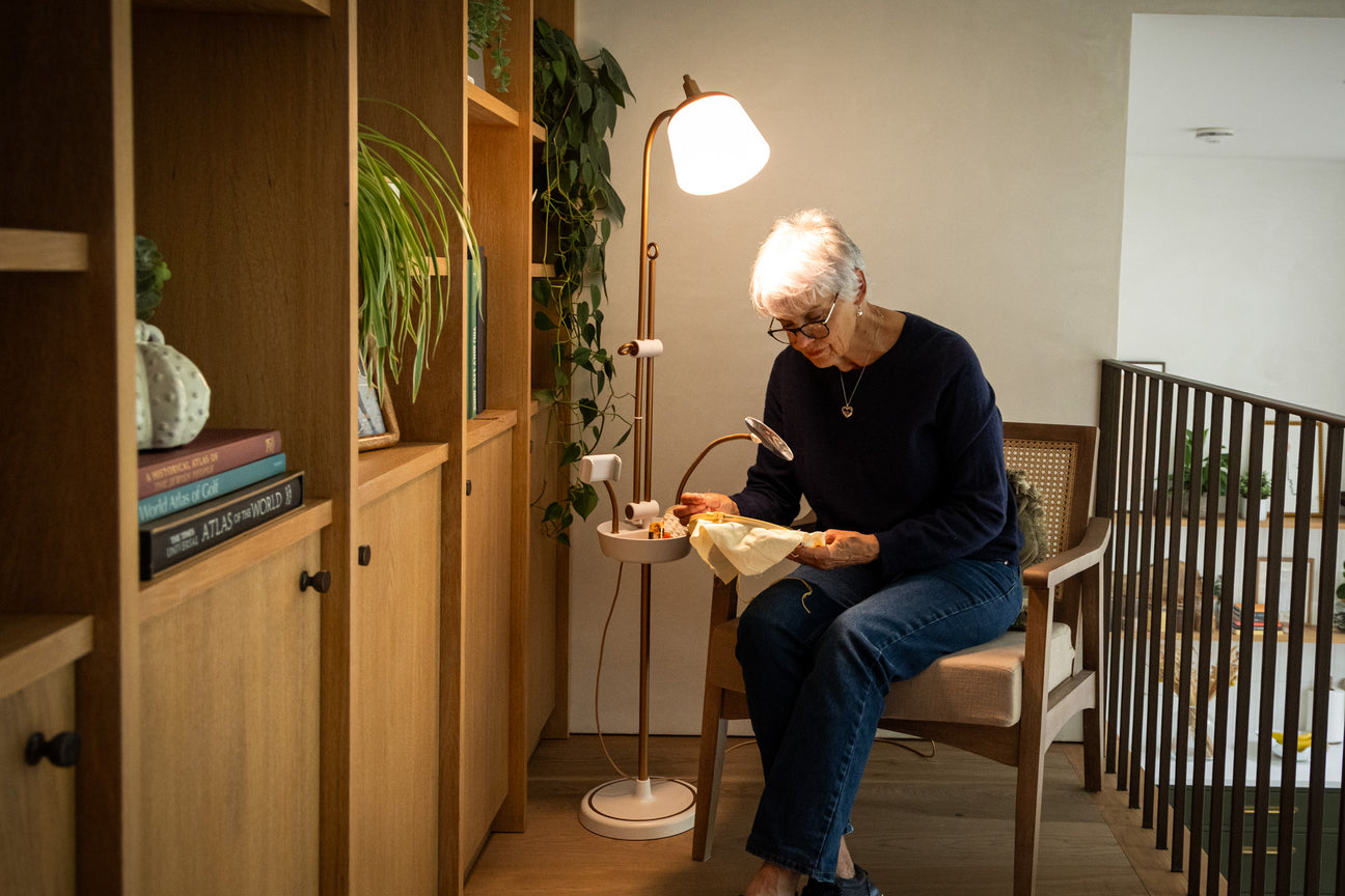 Daylight Anita floor lamp beside a seated crafter using the flexible magnifier and storage tray
