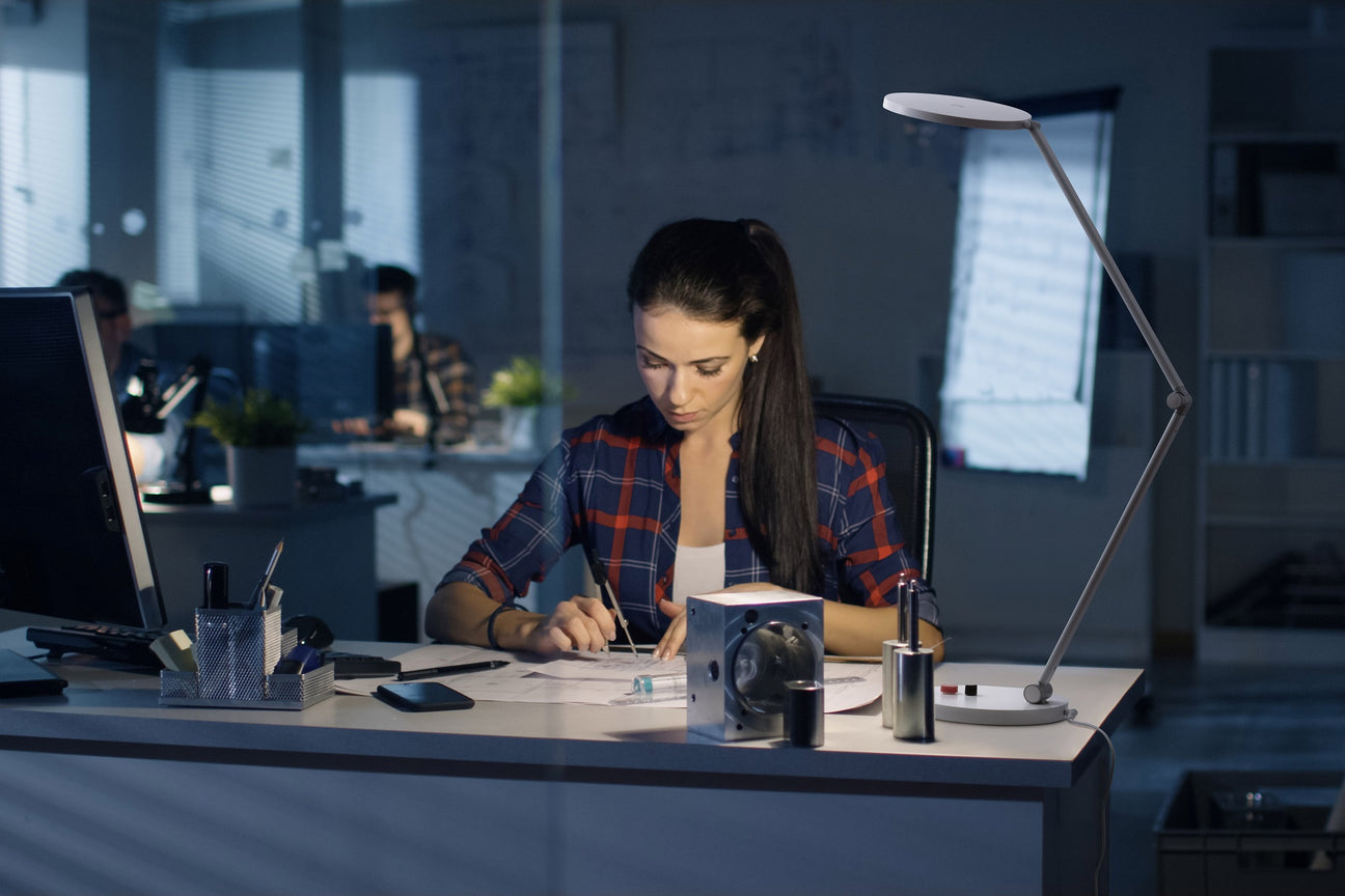Daylight Tricolor table lamp illuminating detailed desk work in an office