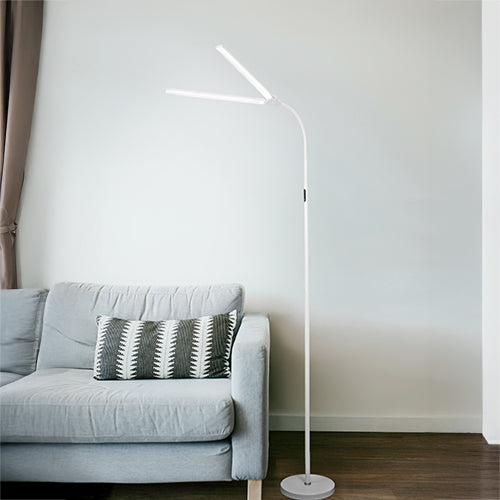 White Triumph Duet dual-head floor lamp beside a lounge chair