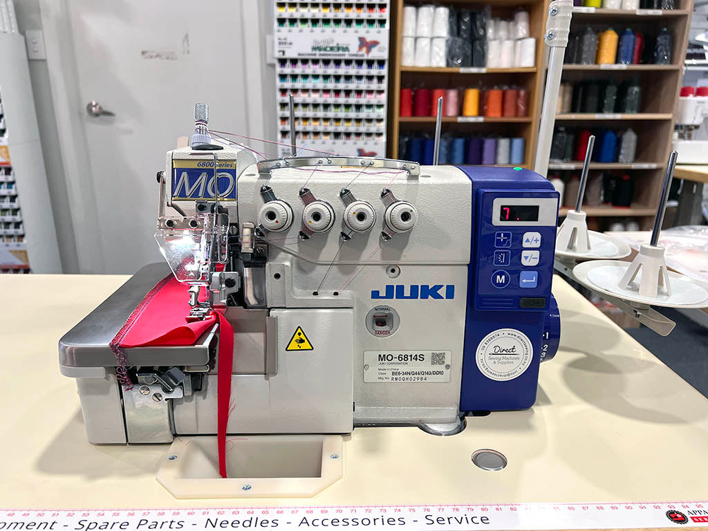 Juki four-thread industrial overlocker, with digital controls and red fabric sample