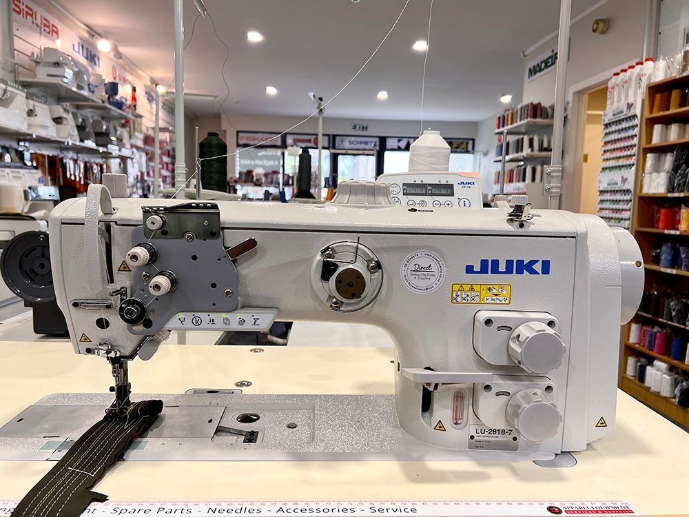 Juki LU-2818A automatic walking foot sewing machine with front controls and a stitched webbing sample on its table