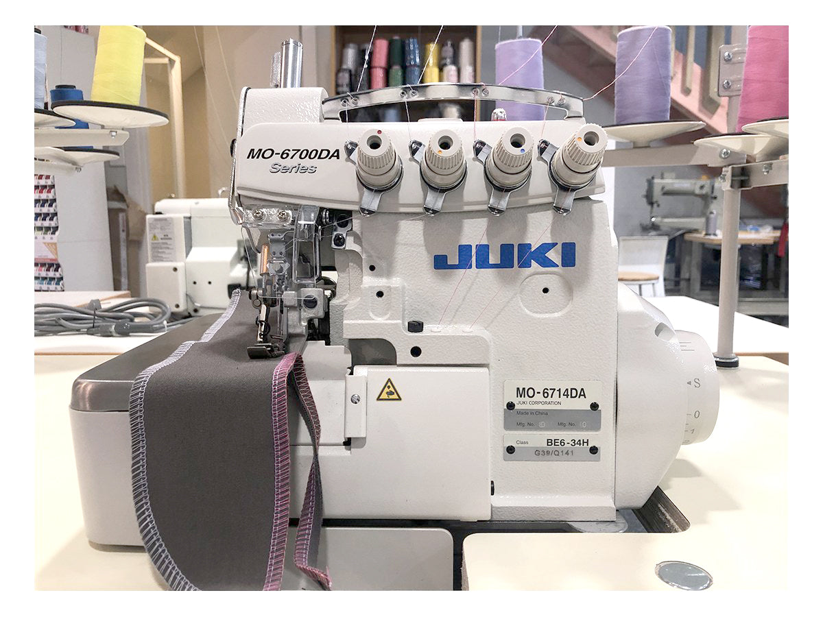Juki MO-6714DA four-thread industrial overlocker, front view with grey fabric sample