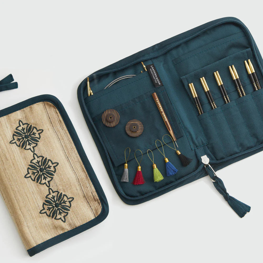 Open Lantern Moon Legacy 13cm interchangeable needle set with five ebony pairs, cables and accessories beside embroidered Khadi silk case