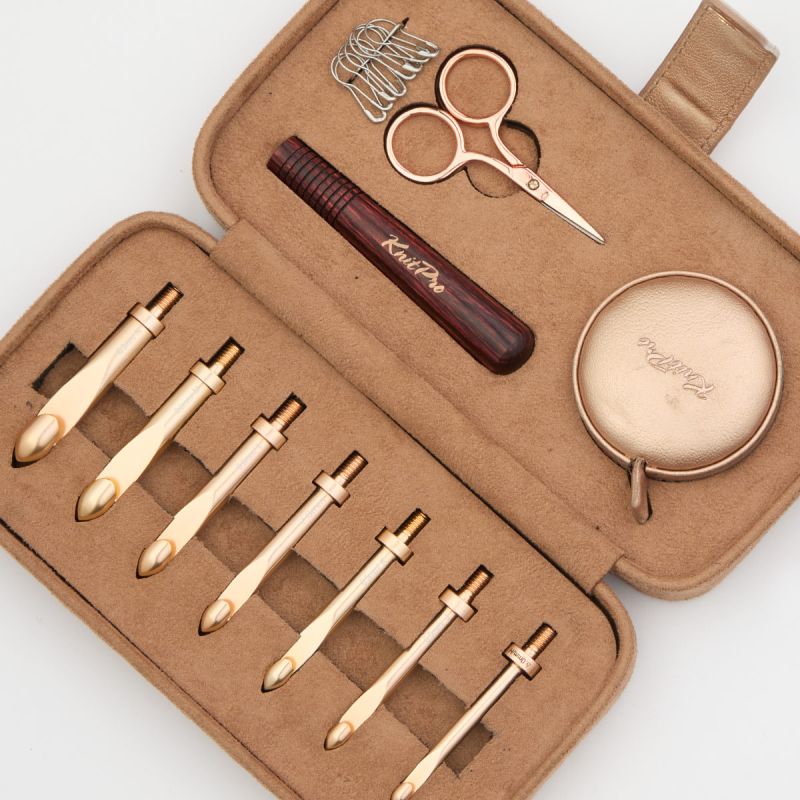 Close view of seven KnitPro Oasis Chunky metal hook heads with rose wooden handle, tape, scissors and locking markers