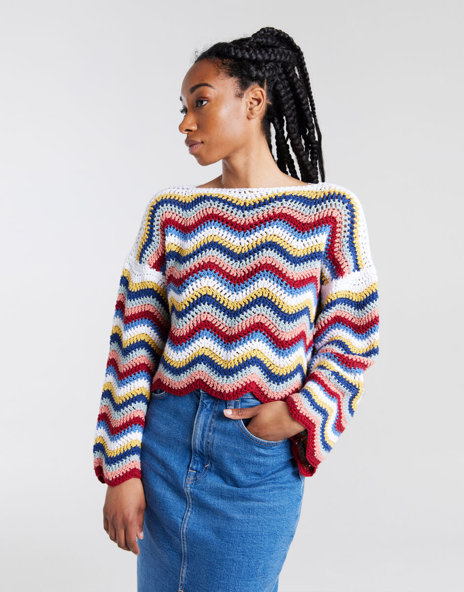 Wool and the Gang Malibu Sweater crochet pattern, model wearing the multicoloured wavy-stripe design